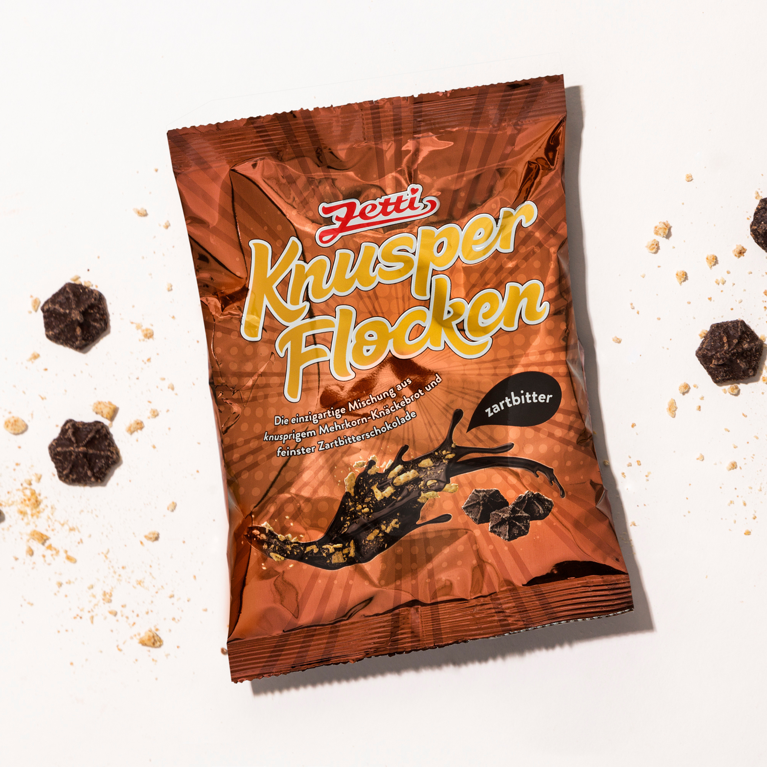 Vorderseite einer Packung Zetti Knusperflocken Zartbitter eingebettet in Zetti Knusperflocken Zartbitter